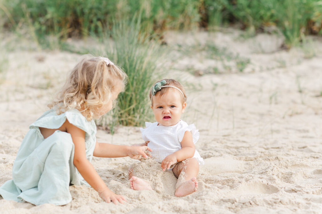 young sisters on the beach playing with sand